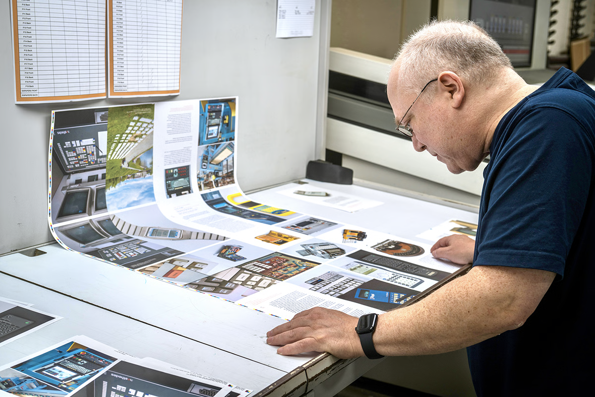 Glenn Fleishman examining printed sheets of Shift Happens on a printing press in Lewiston, Maine